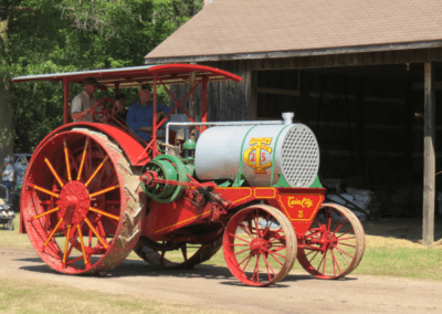 A man and an old man driving a farming/agriculture related vehicle